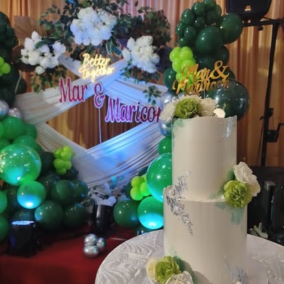 A two-tier wedding cake on the table at a green-and-gold reception